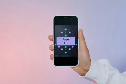 A hand holding a smartphone that displays a digital software interface labeled 'Free Kit' against a soft pink and purple gradient background.
